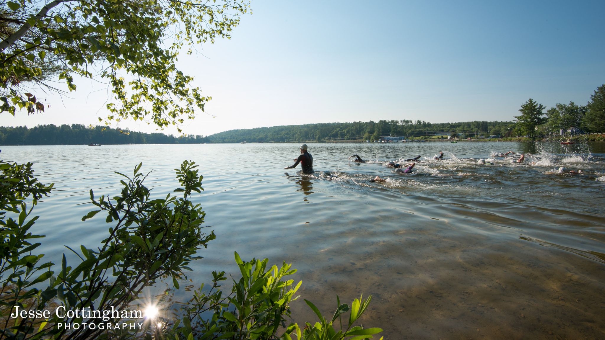 People swimming in a lake with a person standing, bright sunny day. - Witt End and Half Witt Trails Loop