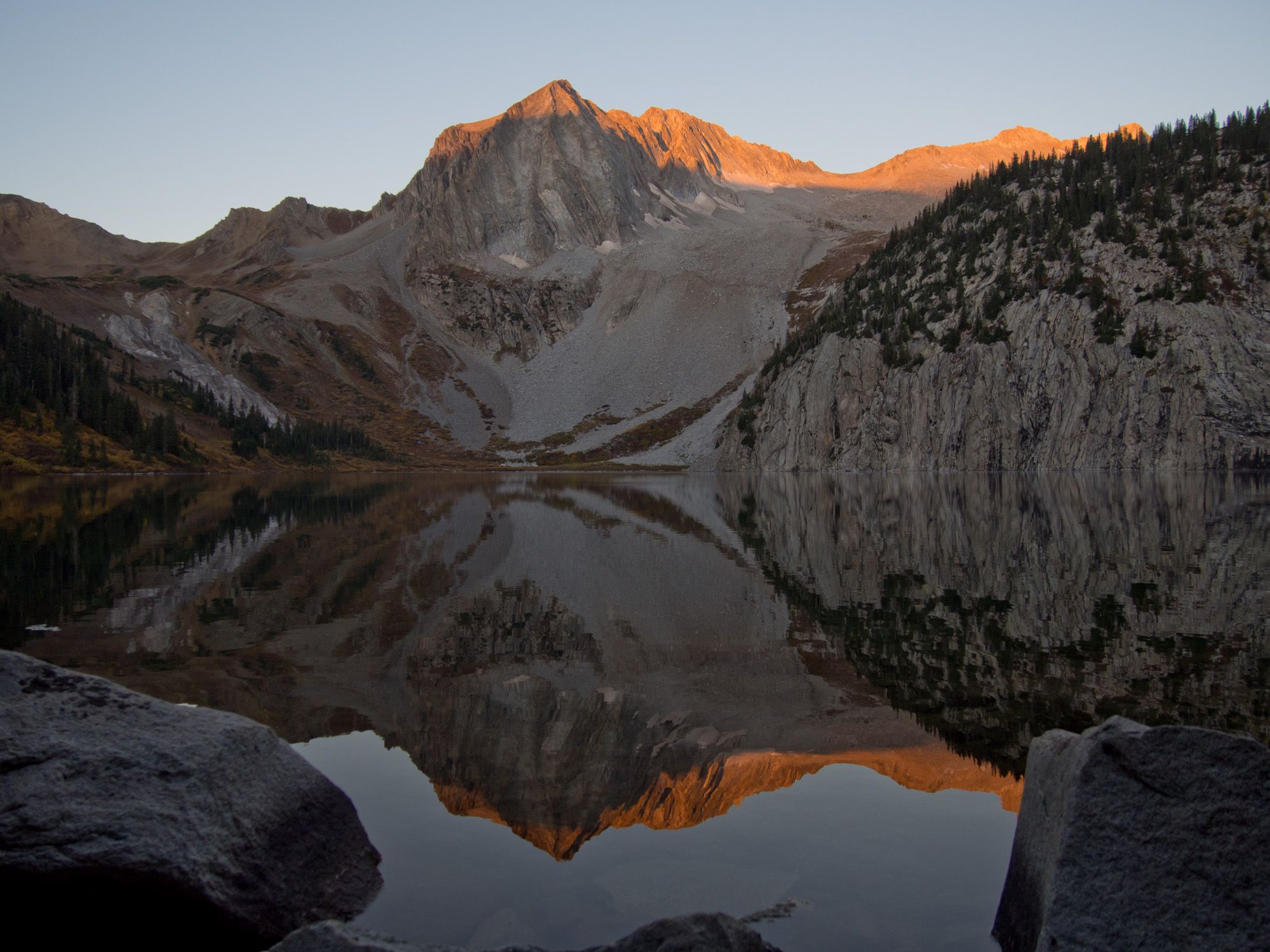 Golden light illuminates a mountain peak reflecting perfectly in a calm lake. - Snowmass Lake via Maroon-Snowmass Trail