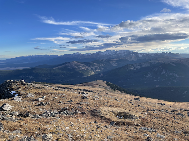 Rugged mountain ridge with distant peaks under a dramatic, cloudy sky at dusk.