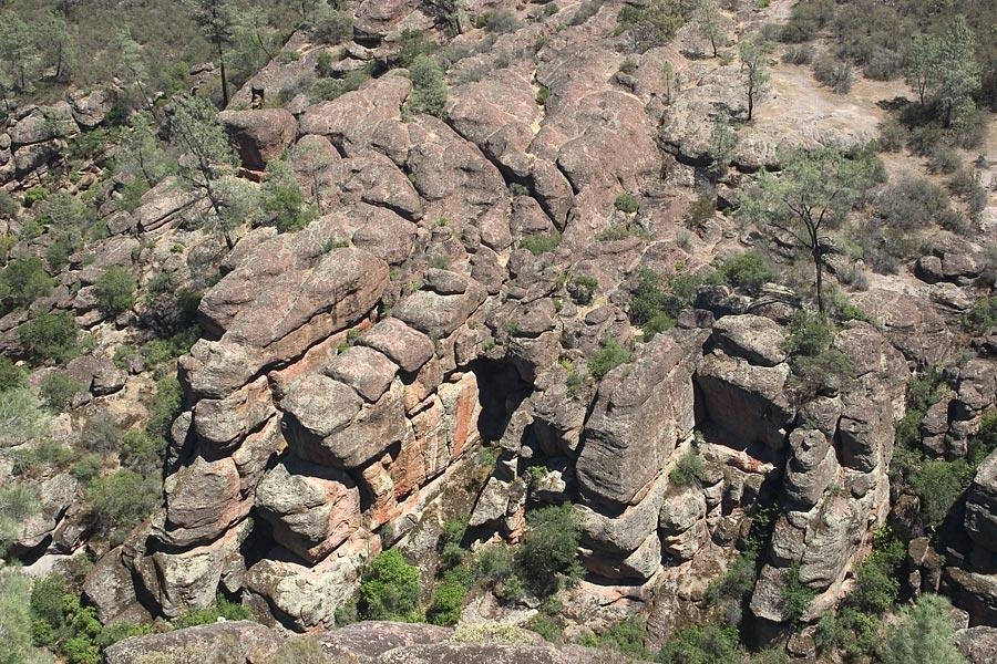Rugged rock formations and sparse green vegetation under bright daylight.