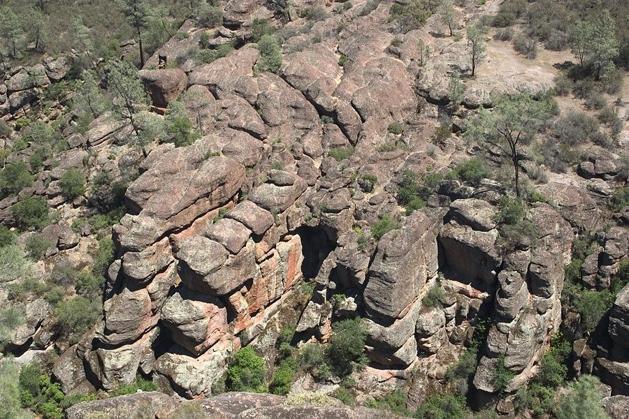 Rugged rock formations and sparse green vegetation under bright daylight. - Moses Spring and Rim Trail Loop