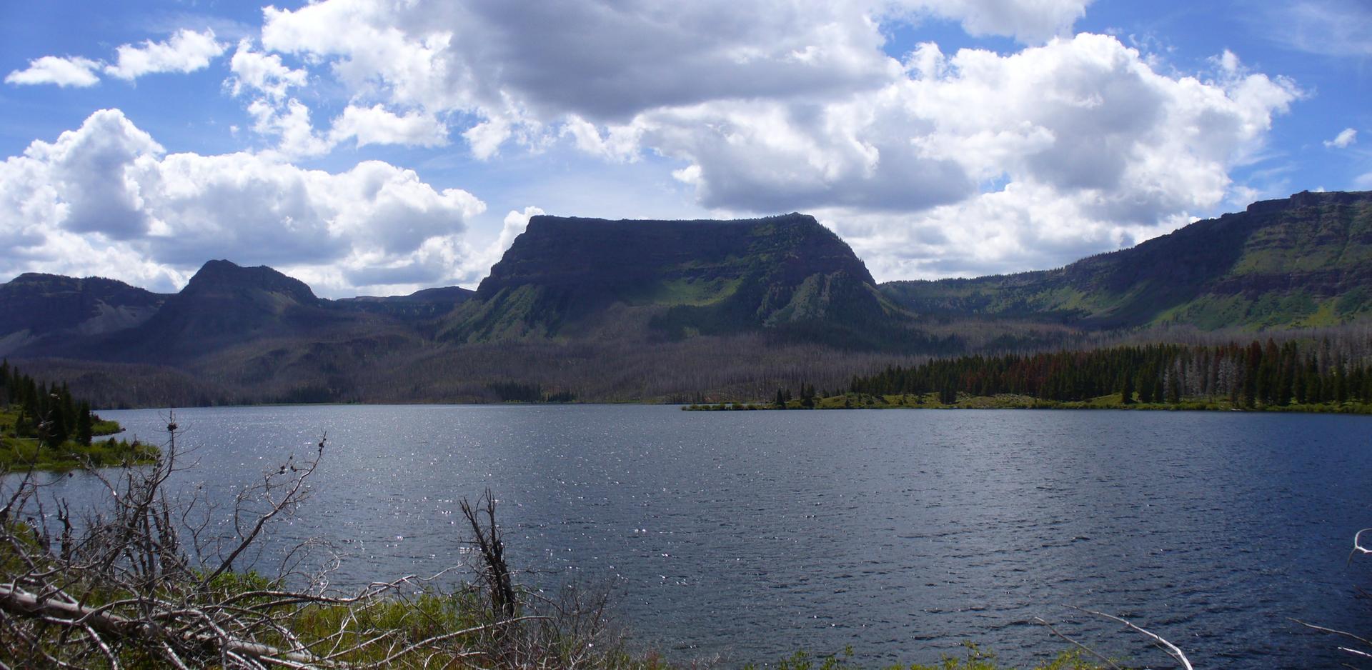 Wide lake with a large, flat-topped mountain under a cloudy sky.