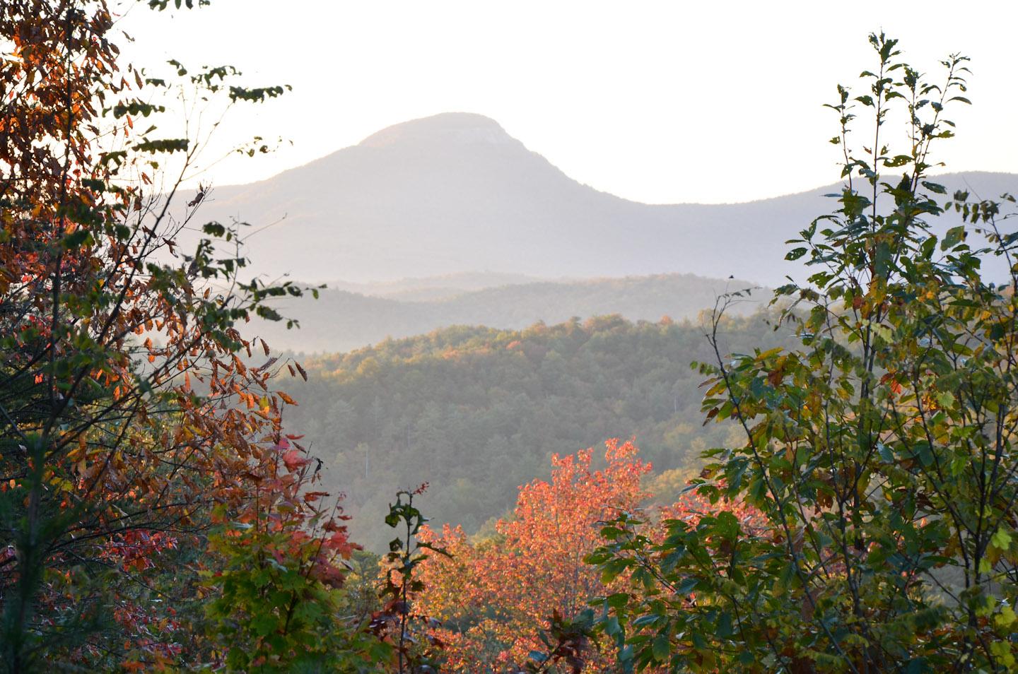 Hazy mountain peaks in the distance with vibrant autumn trees in the foreground.