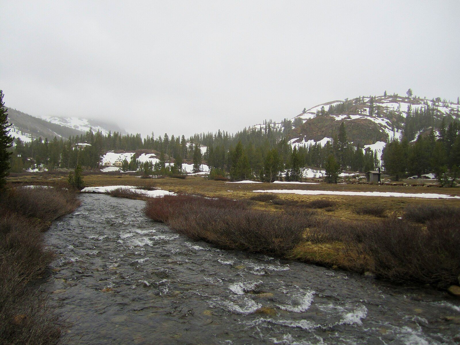 Rushing river through a snowy valley with evergreen trees under an overcast sky. - Maul Lake via Mine Creek Trail