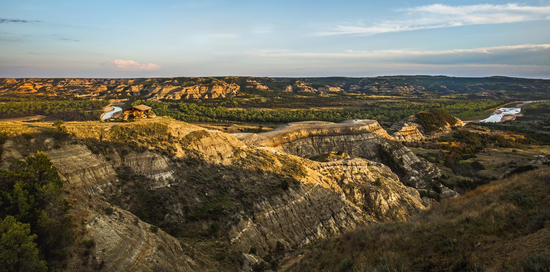 Vast badlands landscape with a winding river under golden hour light.