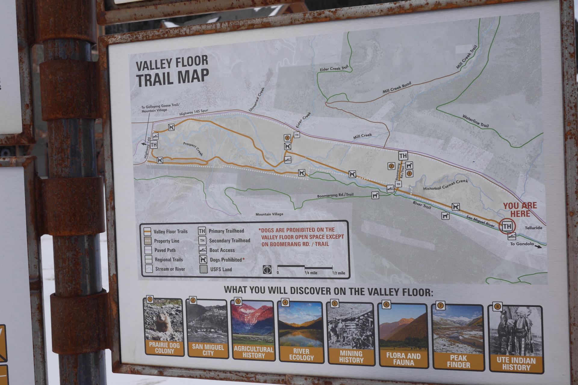 Close-up of a detailed trail map on a weathered outdoor sign.