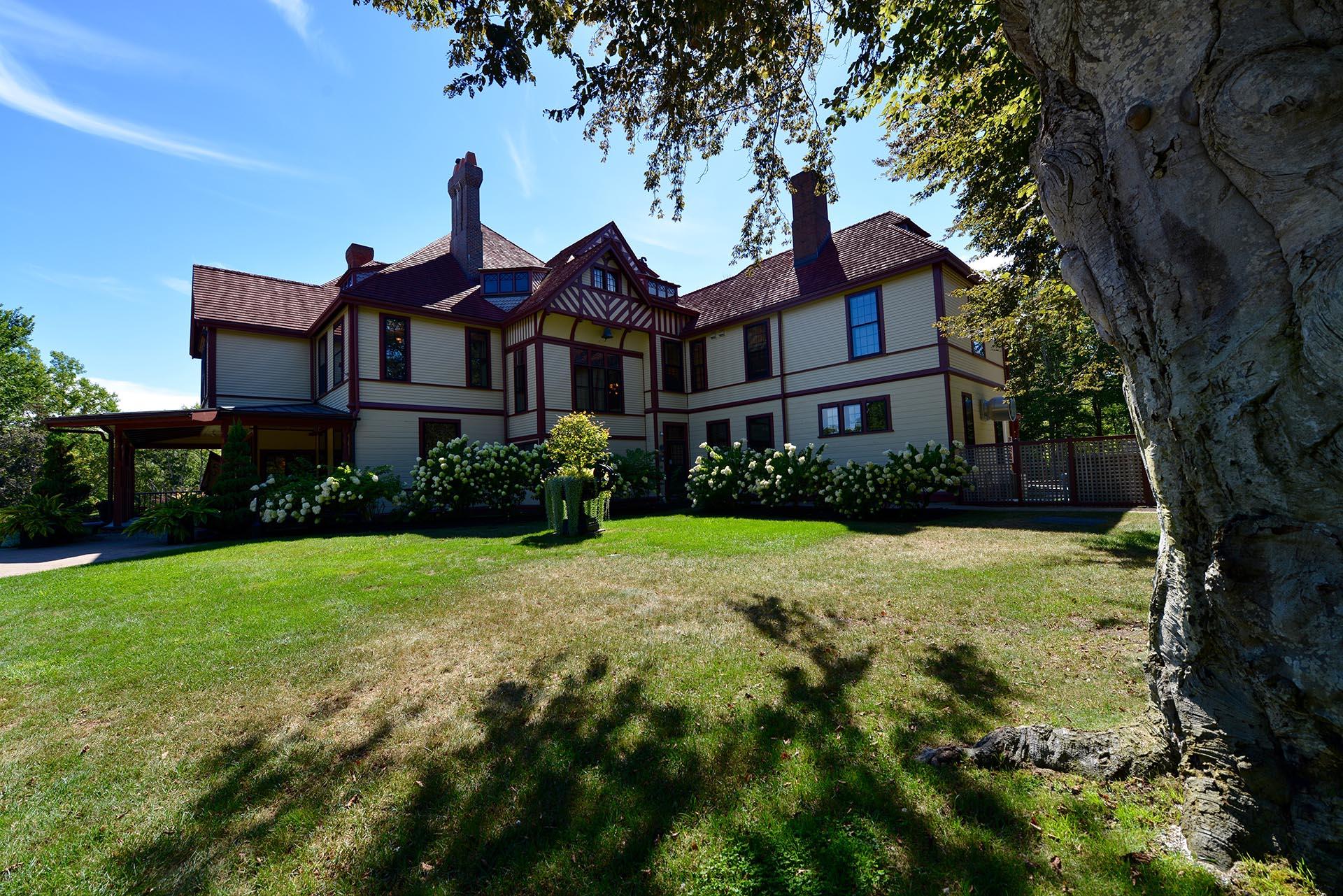 Large, ornate house with green lawn under a bright, sunny sky.