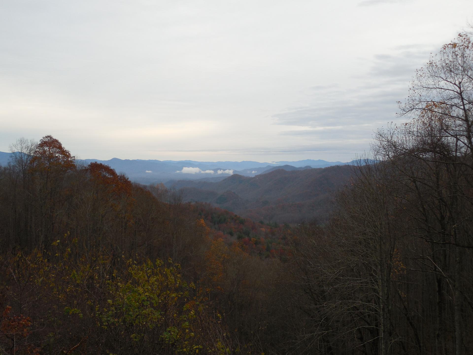 Expansive view of rolling mountains and valleys under an overcast sky.