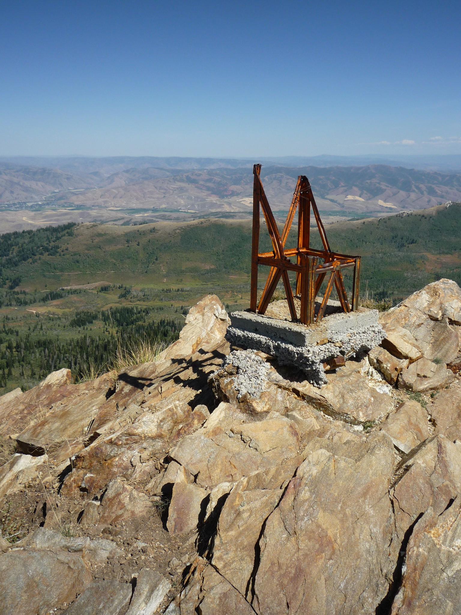 A rusty metal structure on a rocky mountain peak overlooking a vast landscape.