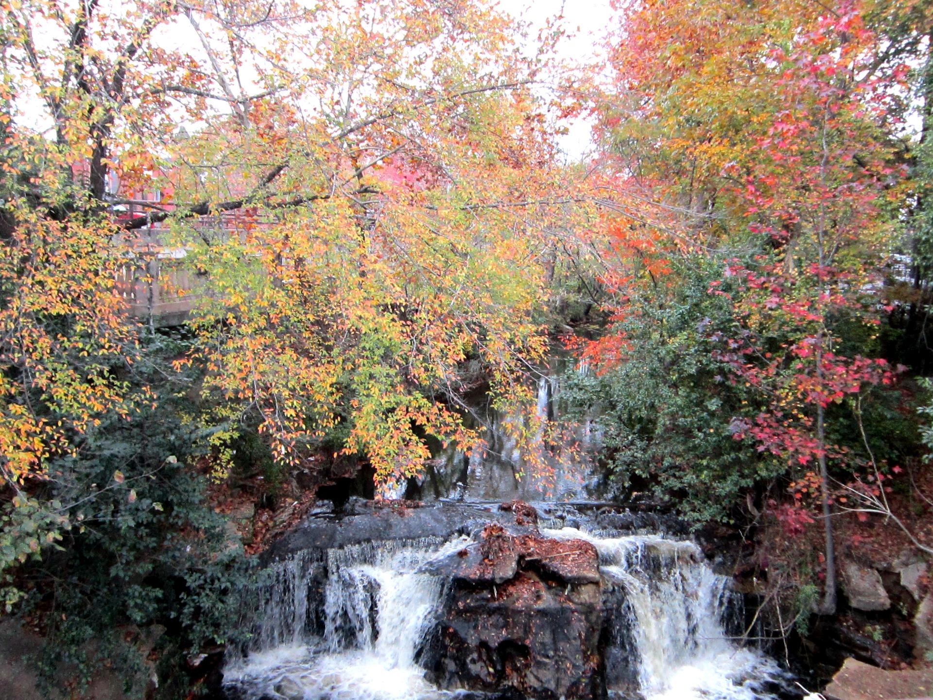 Multi-tiered waterfall surrounded by vibrant red and orange autumn trees.