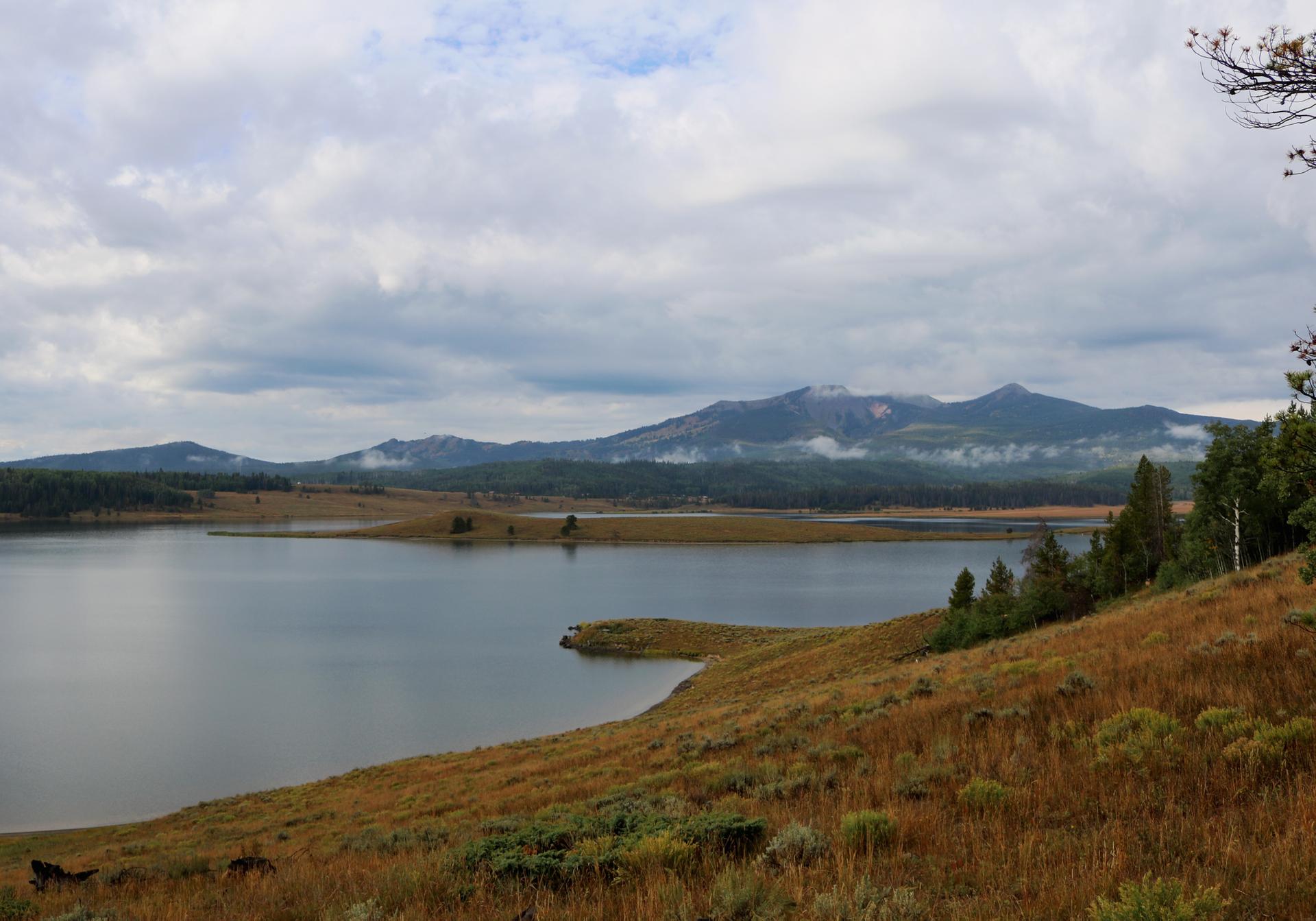 Calm lake with distant misty mountains under an overcast sky.