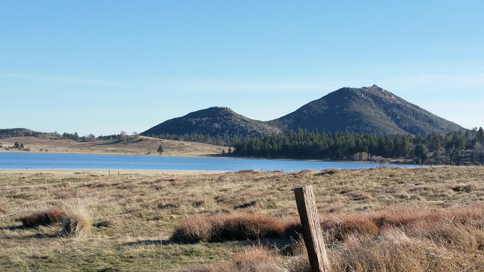 Blue lake nestled between two large mountains under a clear sky.