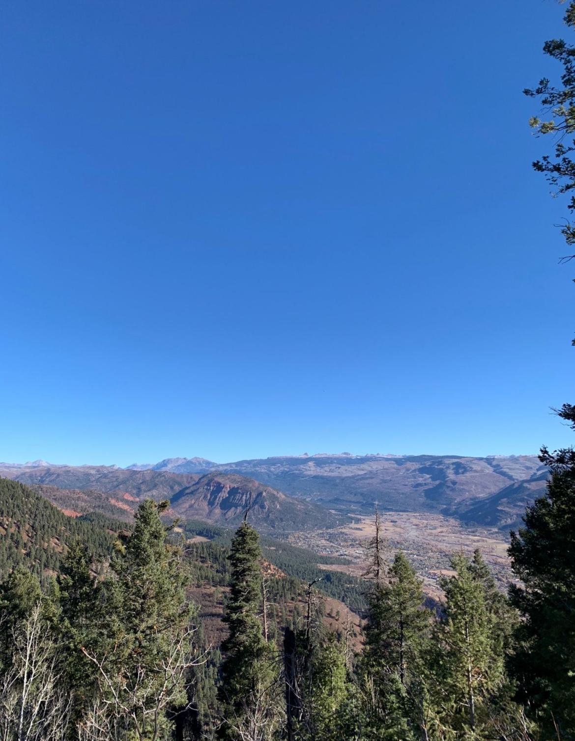 A wide view of a mountain valley under a clear blue sky.