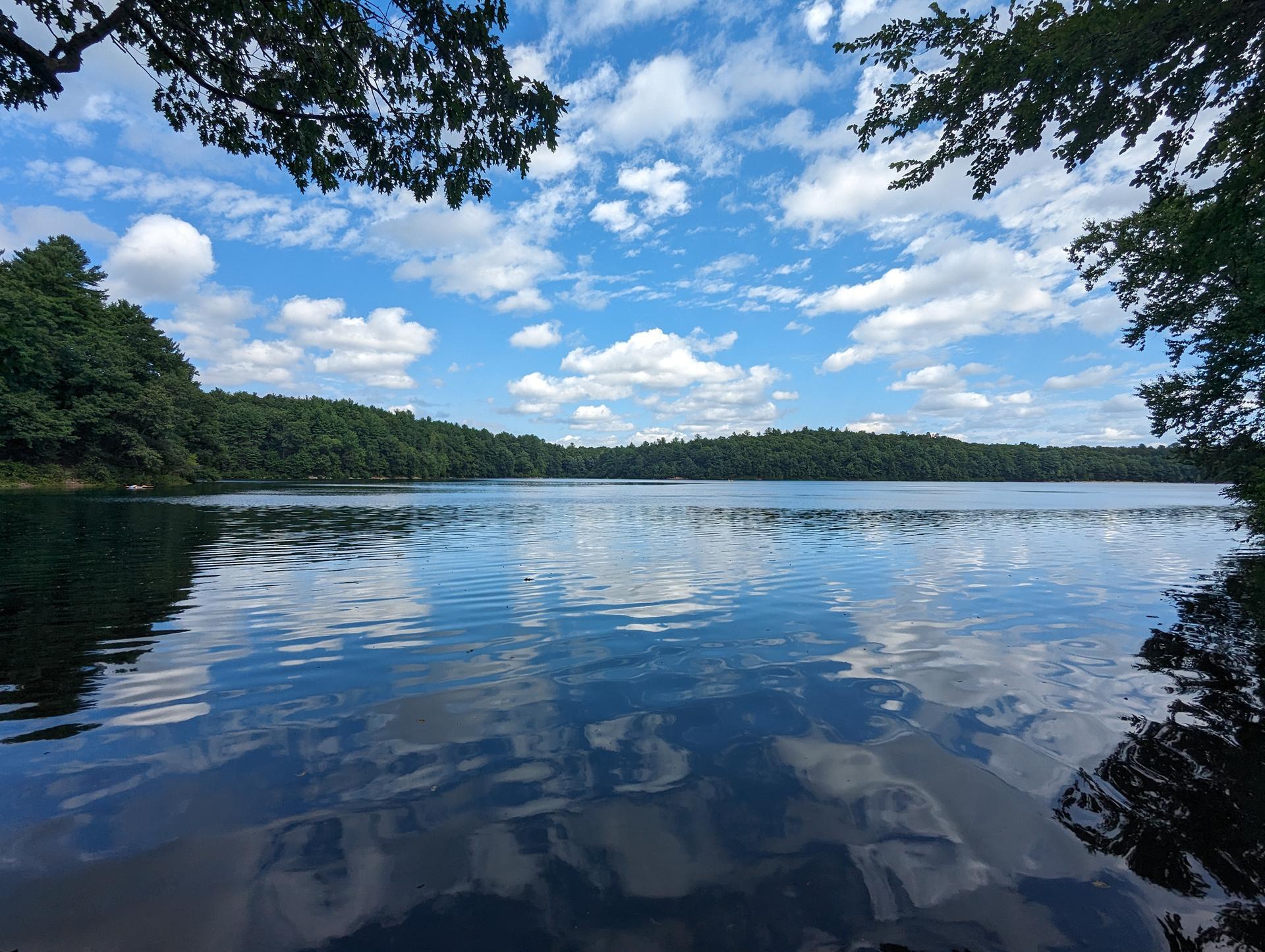 A wide lake reflecting a bright blue sky with white clouds.