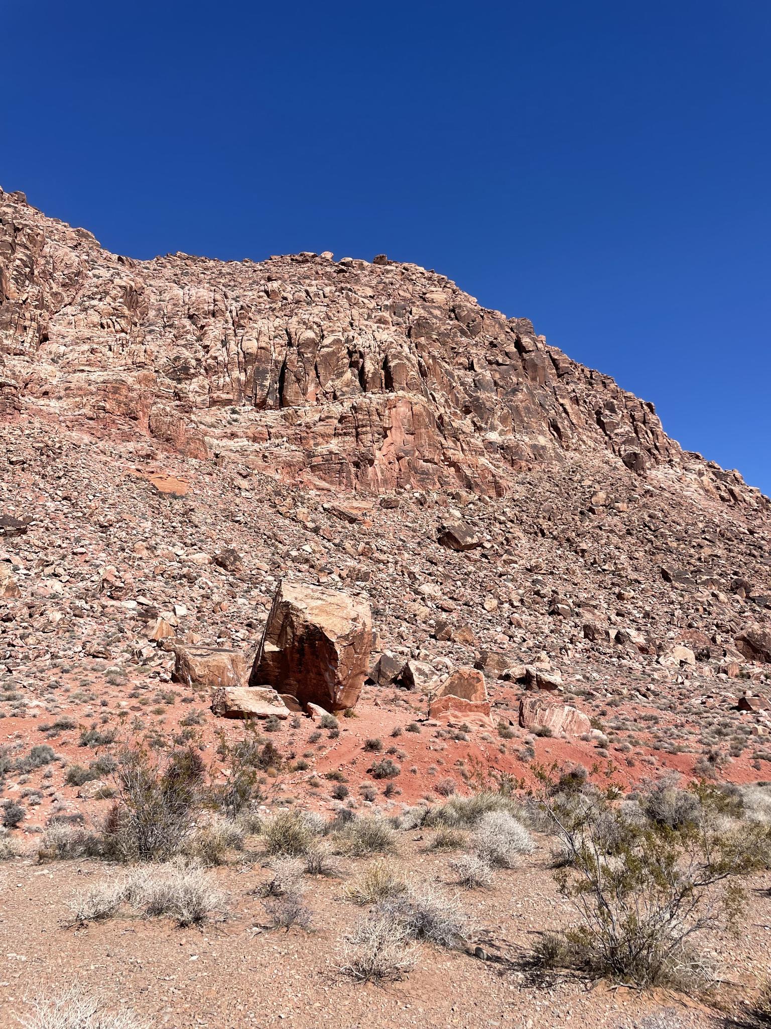 A massive red rock mountain under a clear blue sky.