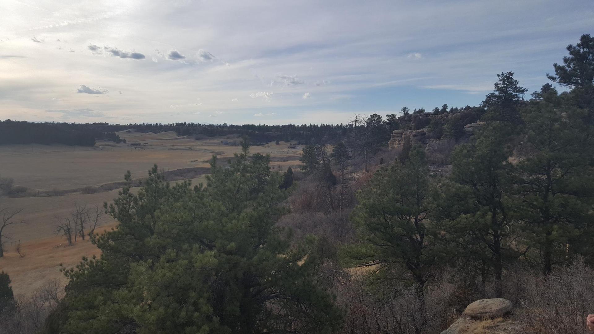 Panoramic view of fields and forests under a cloudy sky.