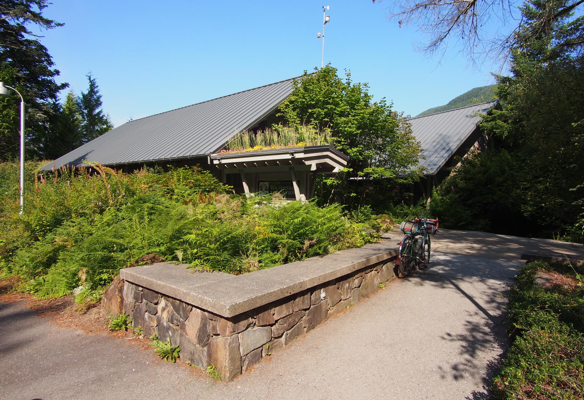 Modern building with green roof and parked bicycles on a sunny day.