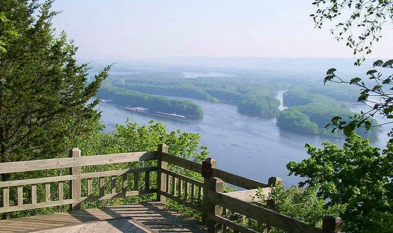Wooden observation deck overlooks a wide river winding through green forested hills.