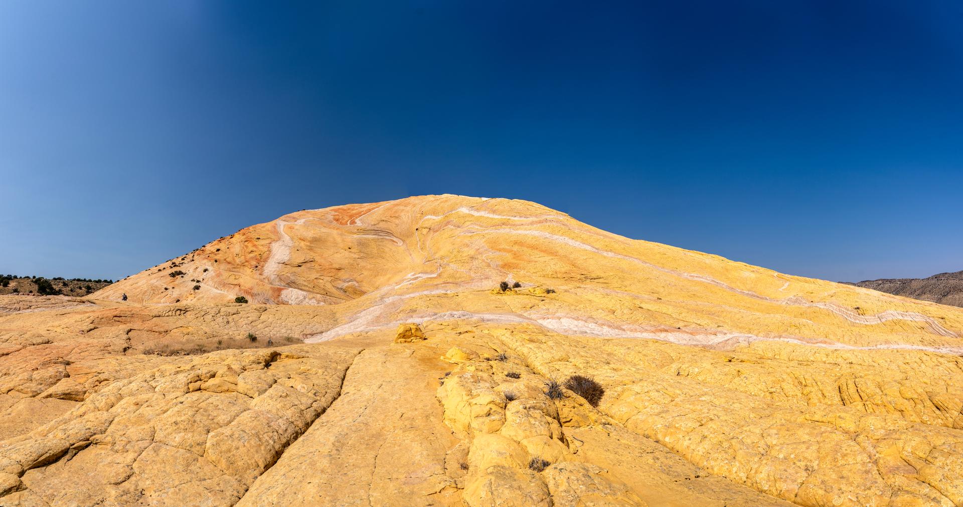 Expansive yellow and white rock formations under a clear blue sky.