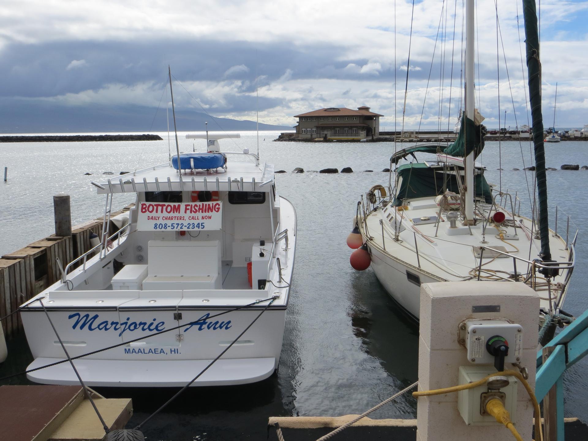 Two boats docked in a harbor under an overcast sky.