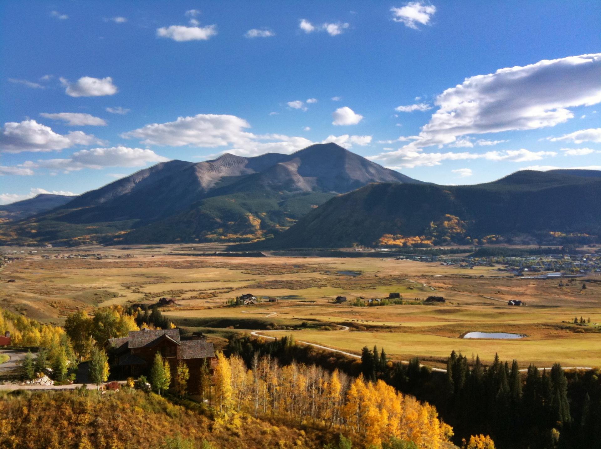 Panoramic view of a wide valley with distant mountains under a blue sky.