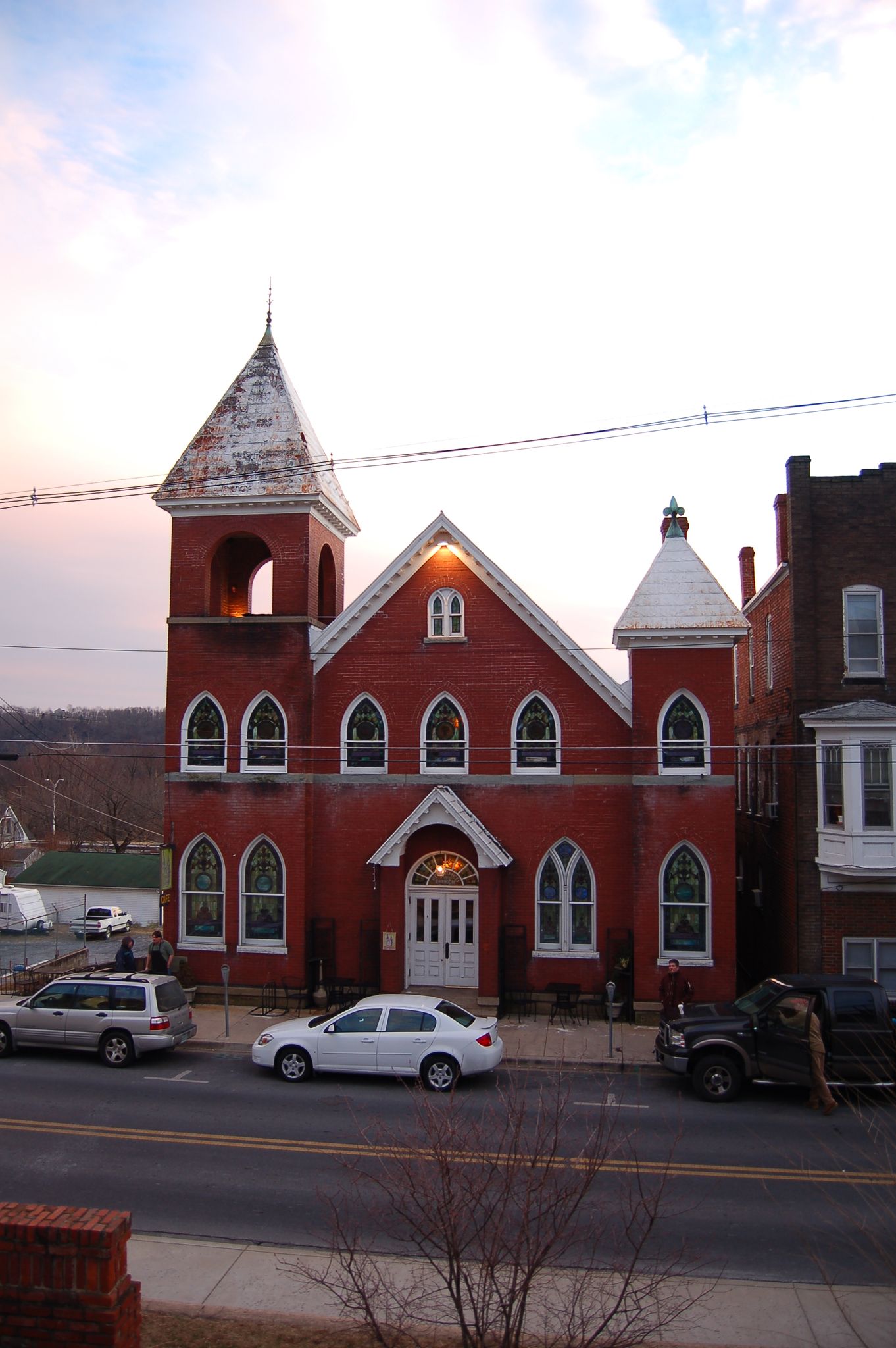 A red brick church with a steeple stands by a street at dusk. - Chesapeake and Ohio Canal Towpath