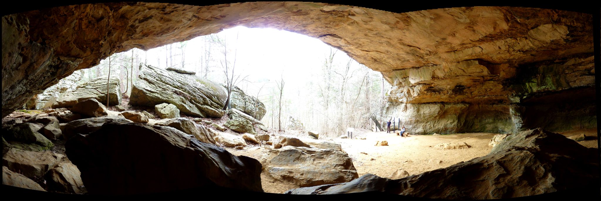 Wide cave entrance with bright light illuminating a sandy floor and rock formations. - Boy Scout and Cedar Creek Trail Loop
