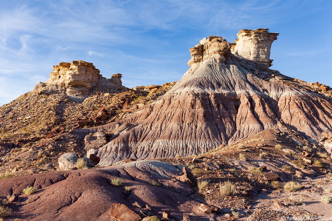 Colorful eroded rock formations with hoodoos under a bright blue sky.