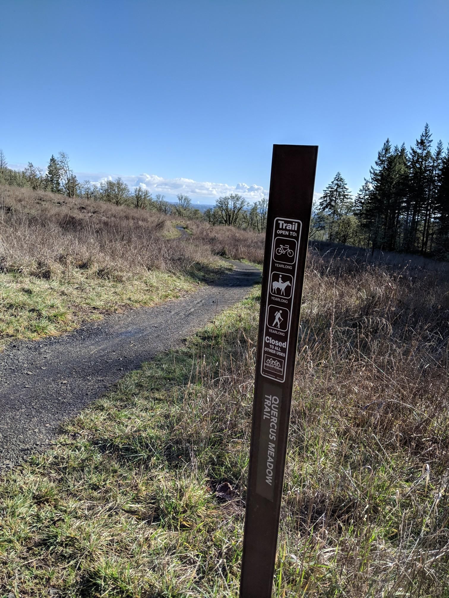 Trail sign next to a gravel path in a sunny, open field. - Chip Ross viewpoint loop from Timberhill Natural Area