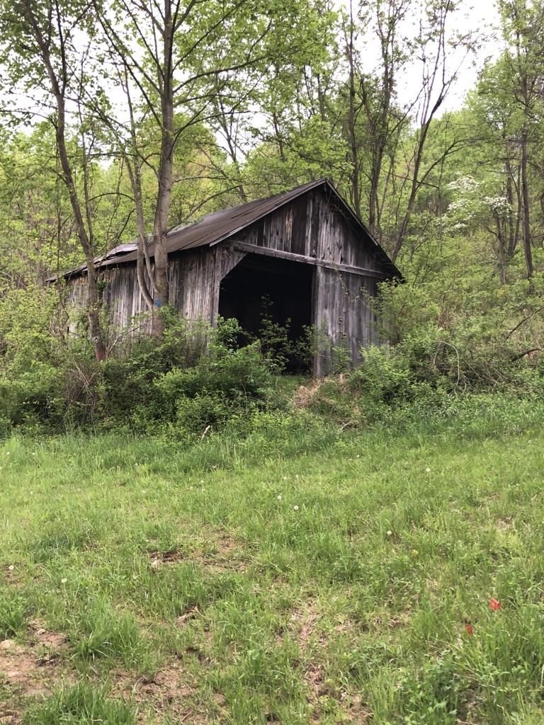 An old wooden barn stands in a grassy field surrounded by trees. - Copper Run and Kepner's Knob Trail Loop