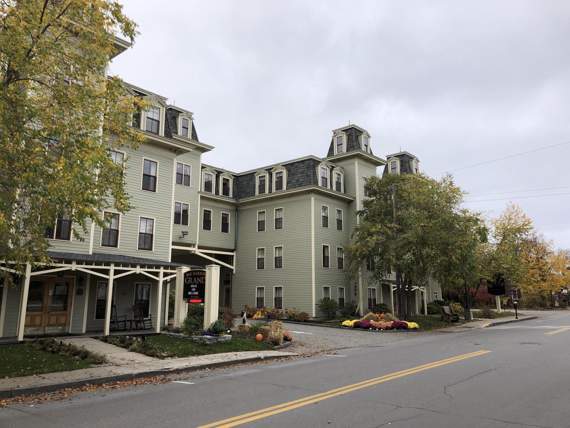 A large, light-green building with autumn decorations on an overcast day.