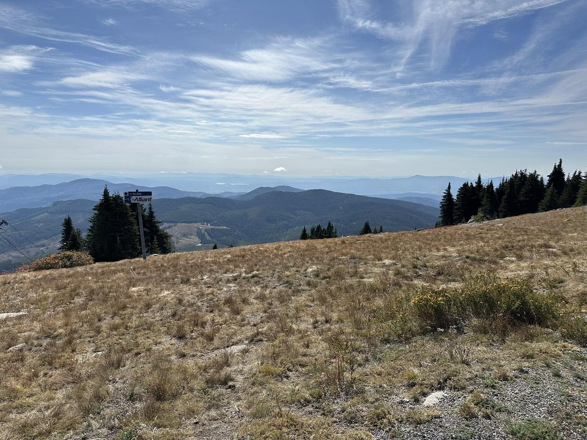 Expansive mountain vista with a grassy foreground under a partly cloudy sky.