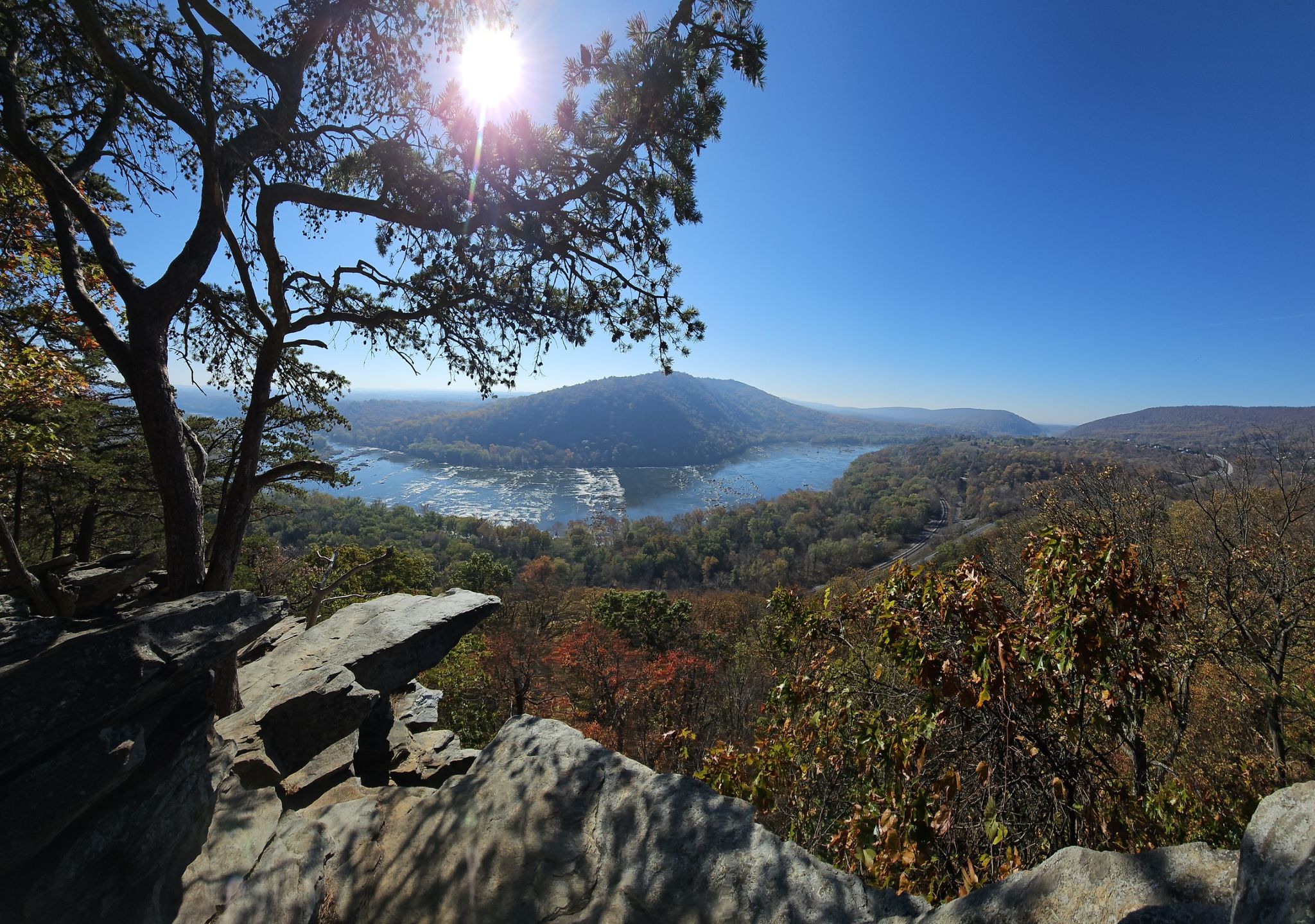 Panoramic view of river and mountains from rocky overlook, bright sun. - Weverton Cliffs