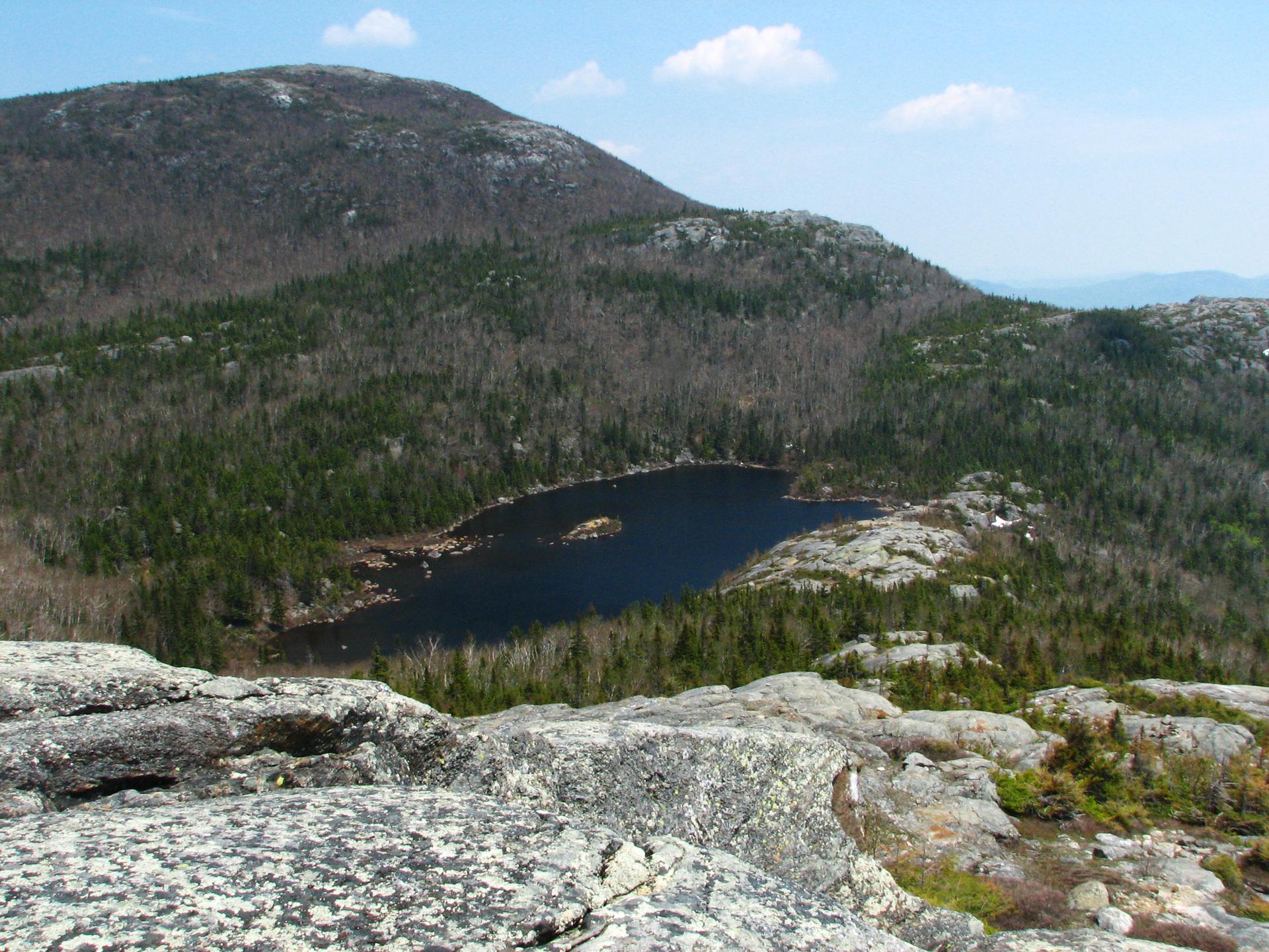 Elevated view of a dark mountain lake surrounded by forested peaks.