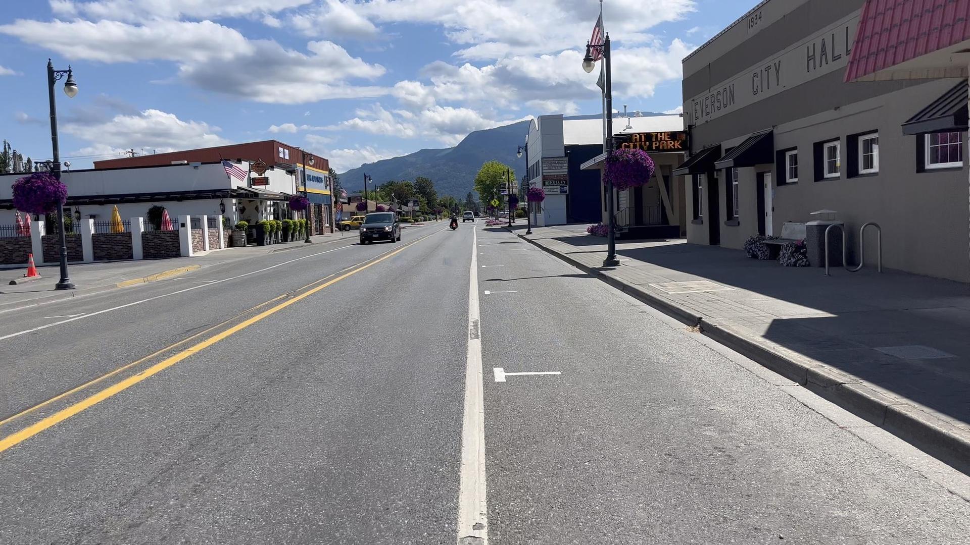 Sunny street in a small town with buildings and distant mountains.