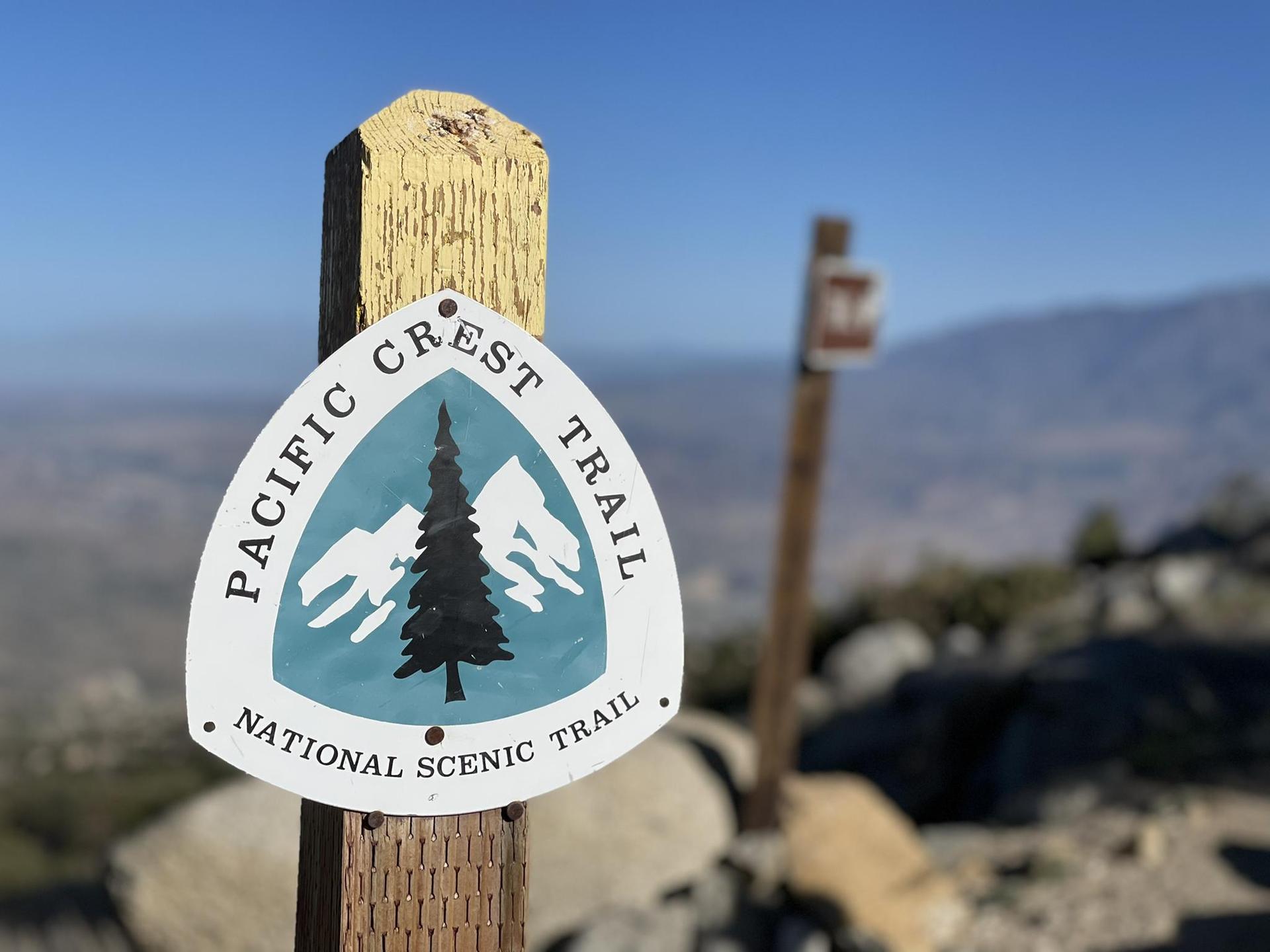 Close-up of a "Pacific Crest Trail" sign on a wooden post.