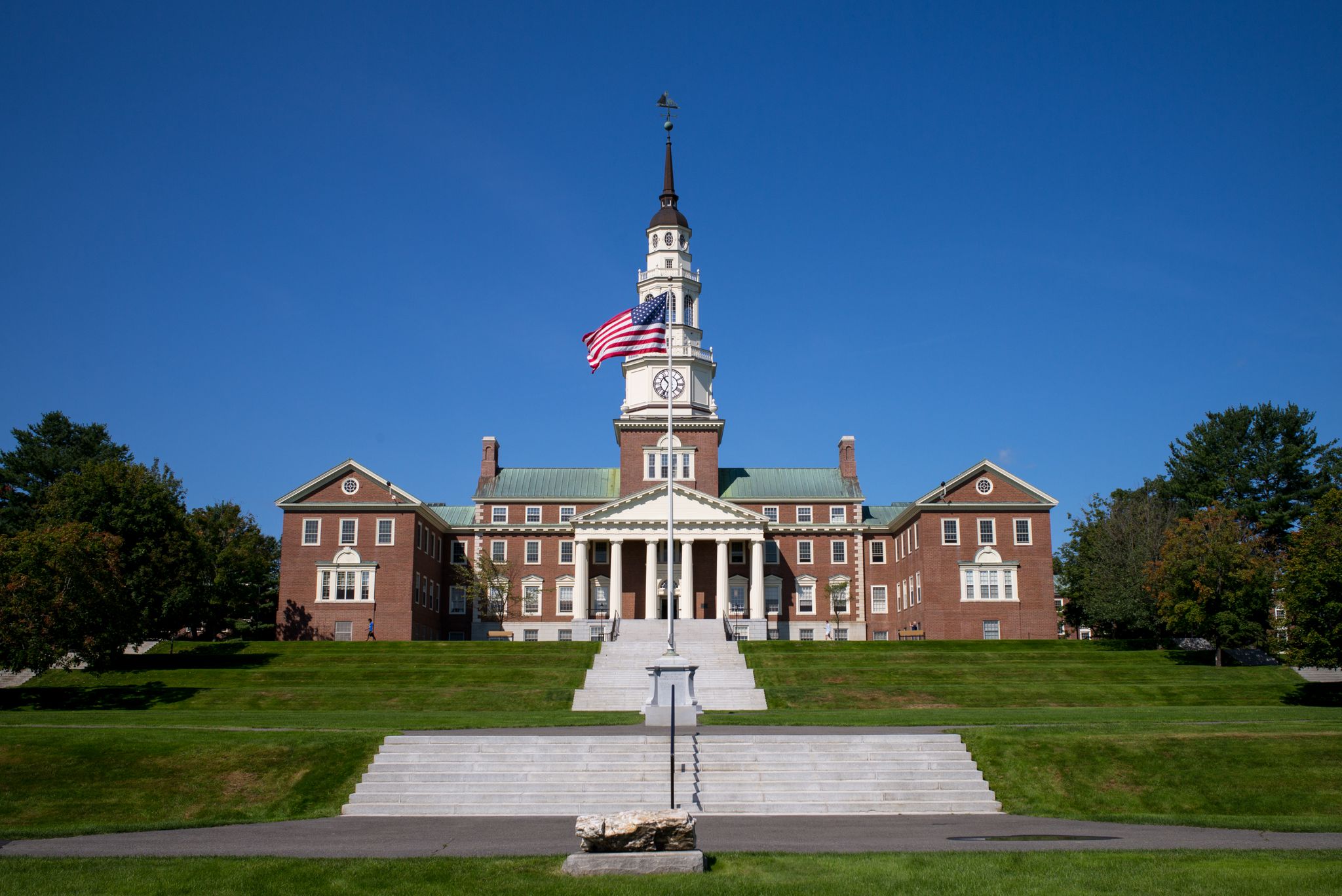 Grand brick building with a clock tower and flag on a sunny day. - Waterville, Maine – Mill Island Park loop from Fairfield