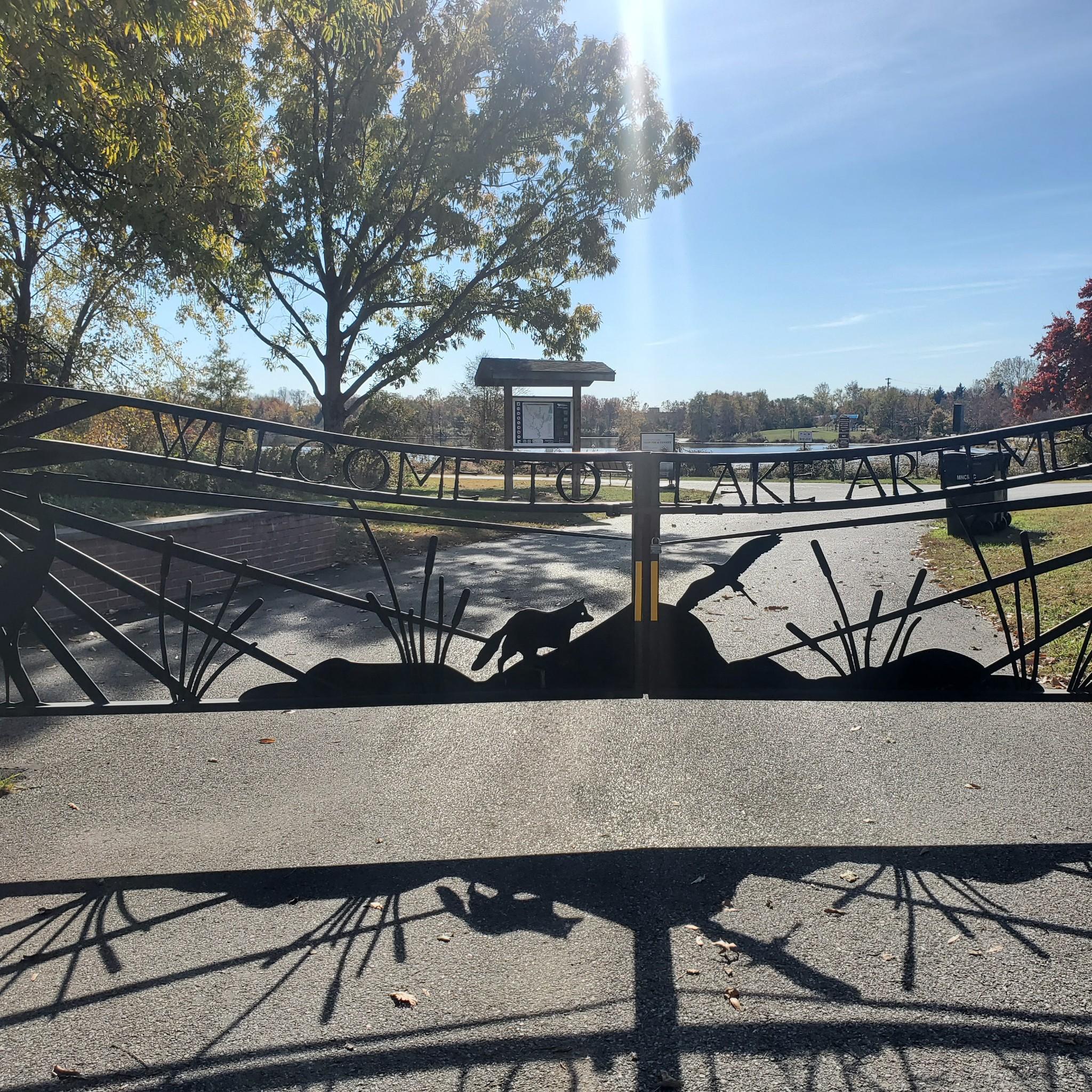 A decorative metal gate with animal silhouettes on a sunny path.