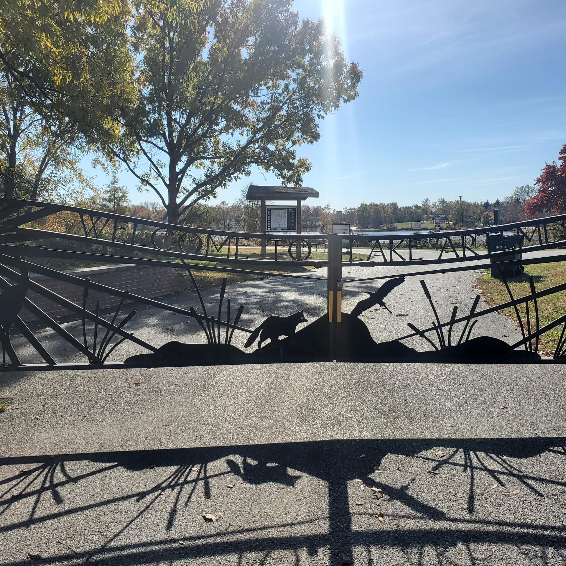 A decorative metal gate with animal silhouettes on a sunny path.