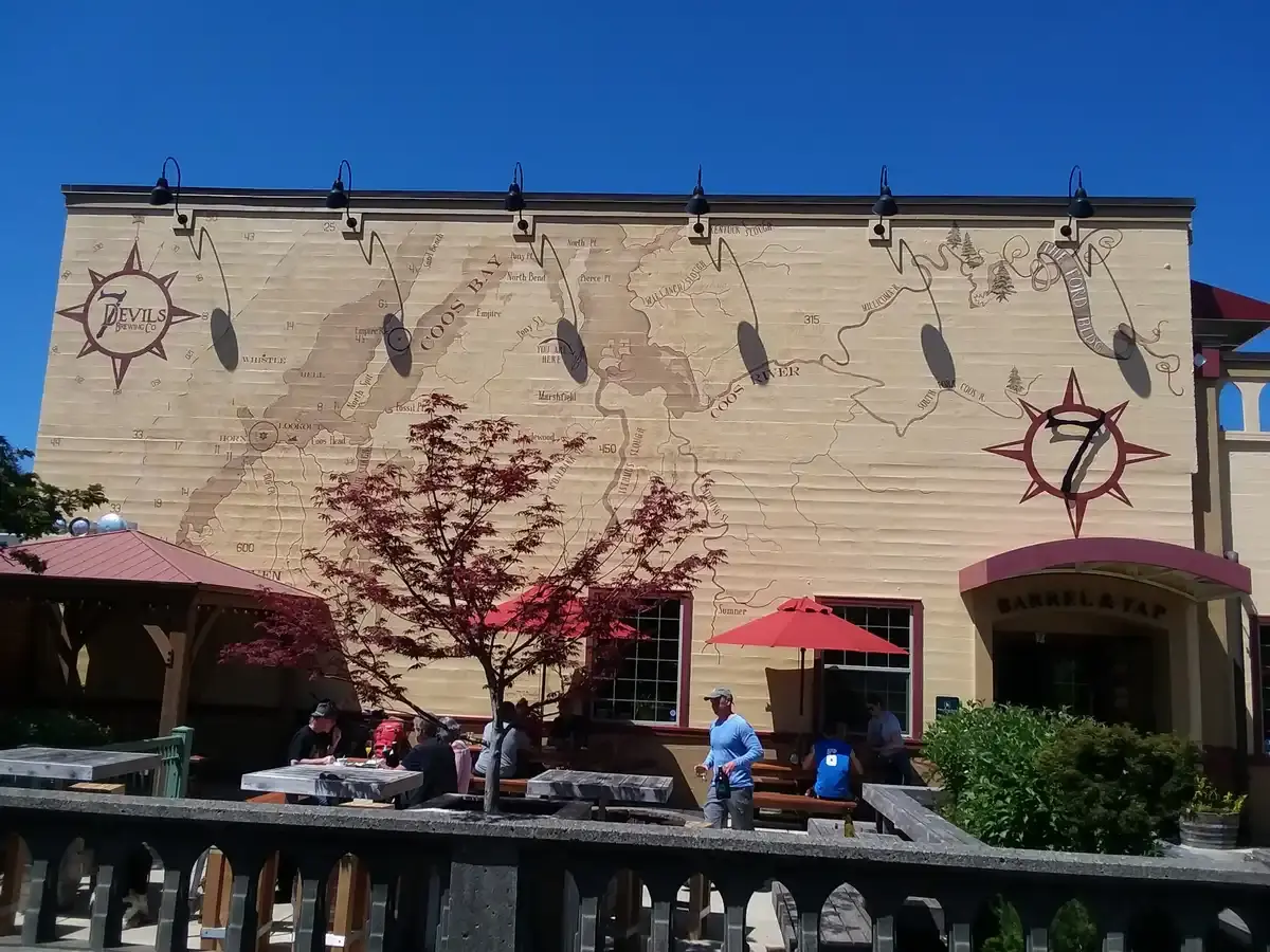 Building with a large map mural and people dining on a sunny outdoor patio.