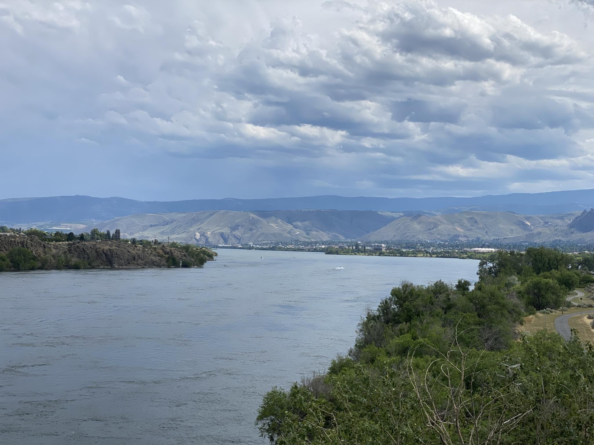 Wide river with forested banks, distant mountains under a cloudy sky. - Apple Capital Recreation Loop Trail