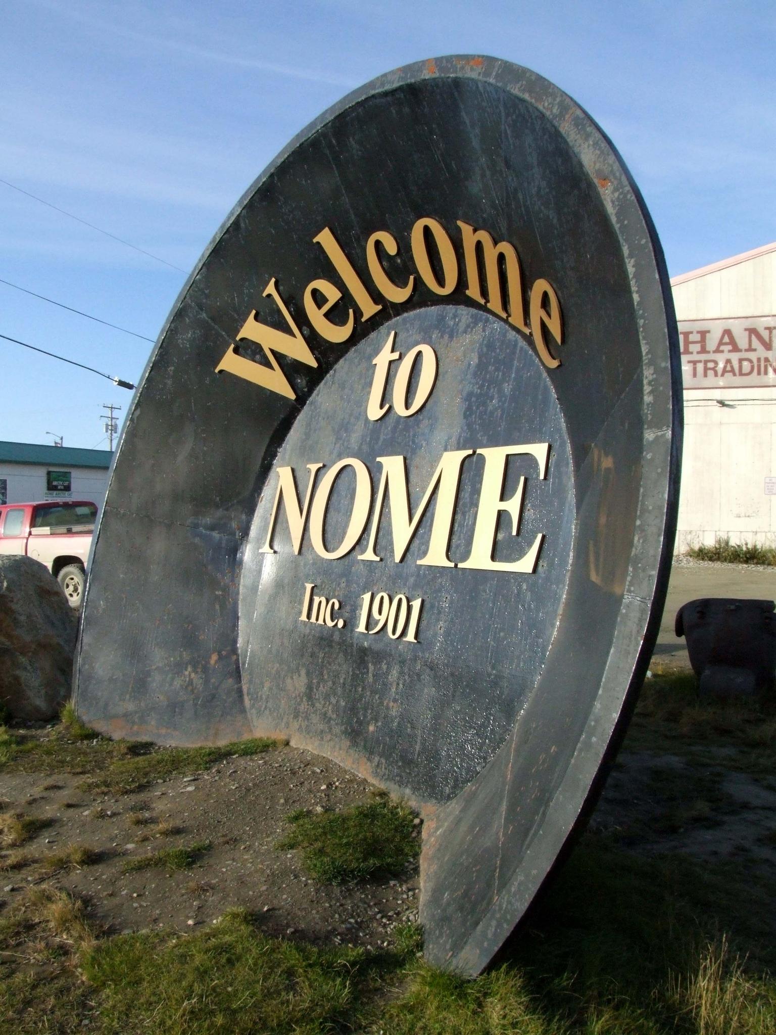 Large, dark, curved sign with 'Welcome to' and 'Inc. 1901' in gold letters.