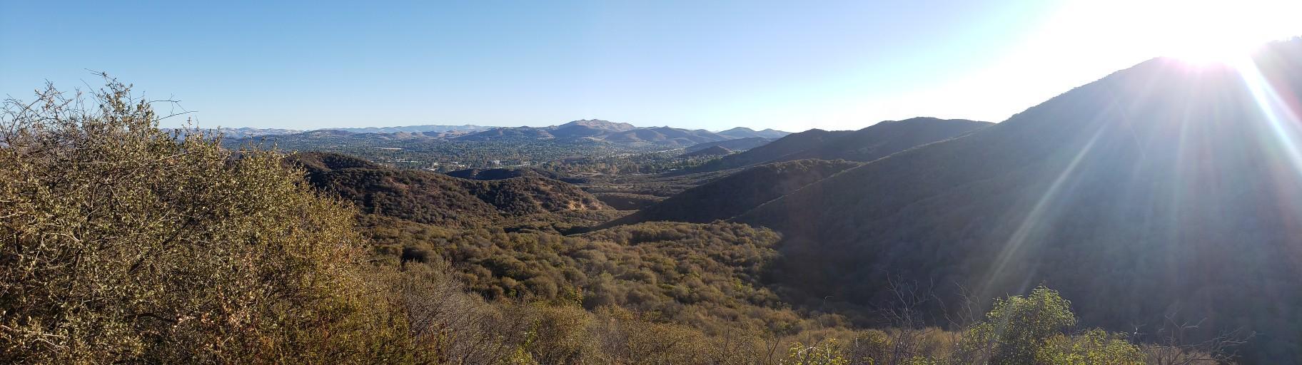 Sunny panoramic view of hills and valleys with bright sun flare.