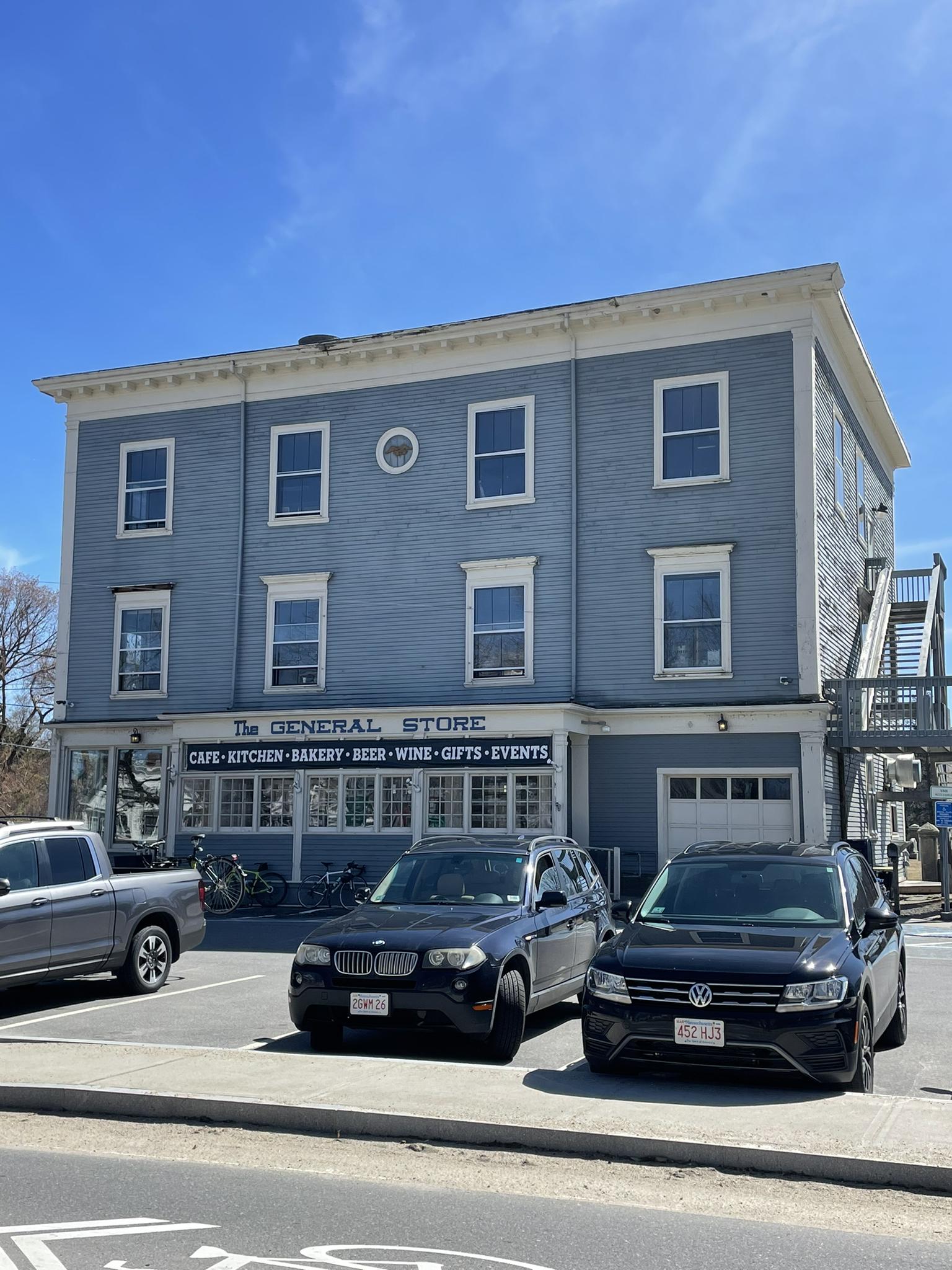 Light blue general store building with parked cars under a bright sunny sky.