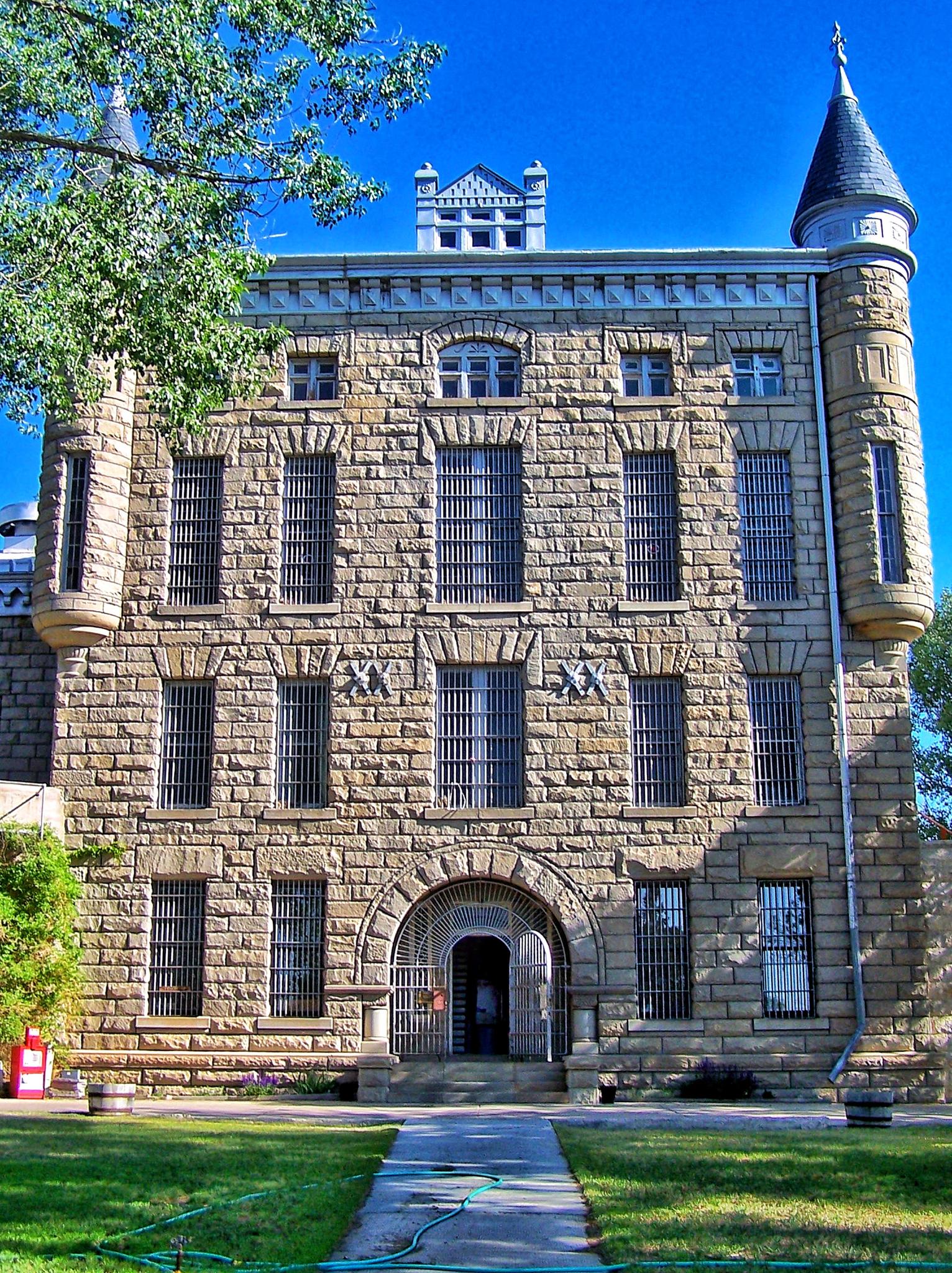 A large, ornate stone building with barred windows and a prominent turret.