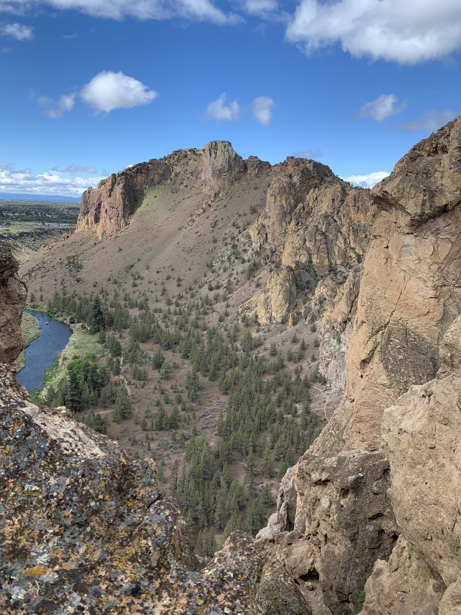 Deep canyon with a winding river and steep rocky cliffs under a cloudy sky.