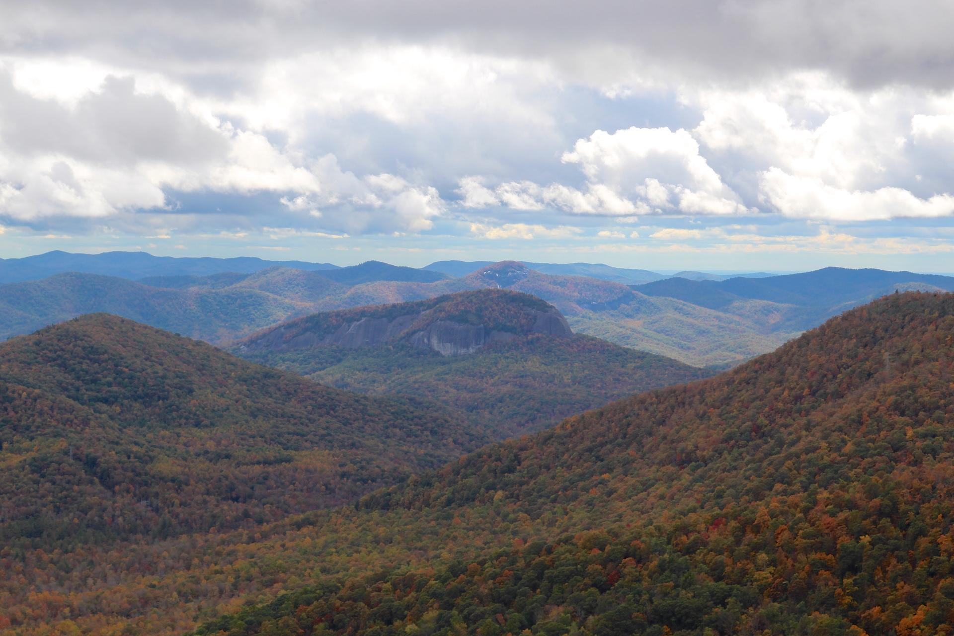 Expansive view of forested mountains under a cloudy sky.