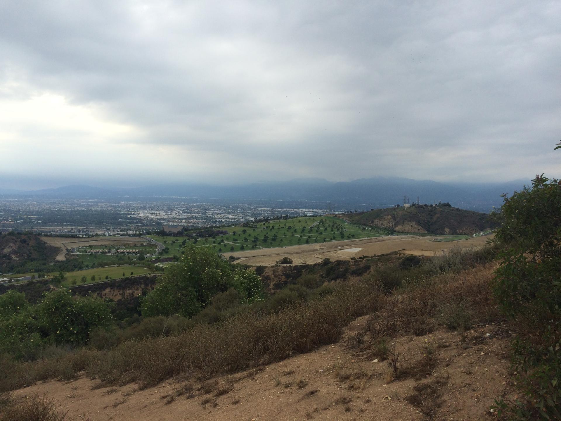 Panoramic view of a valley and distant city under an overcast sky.