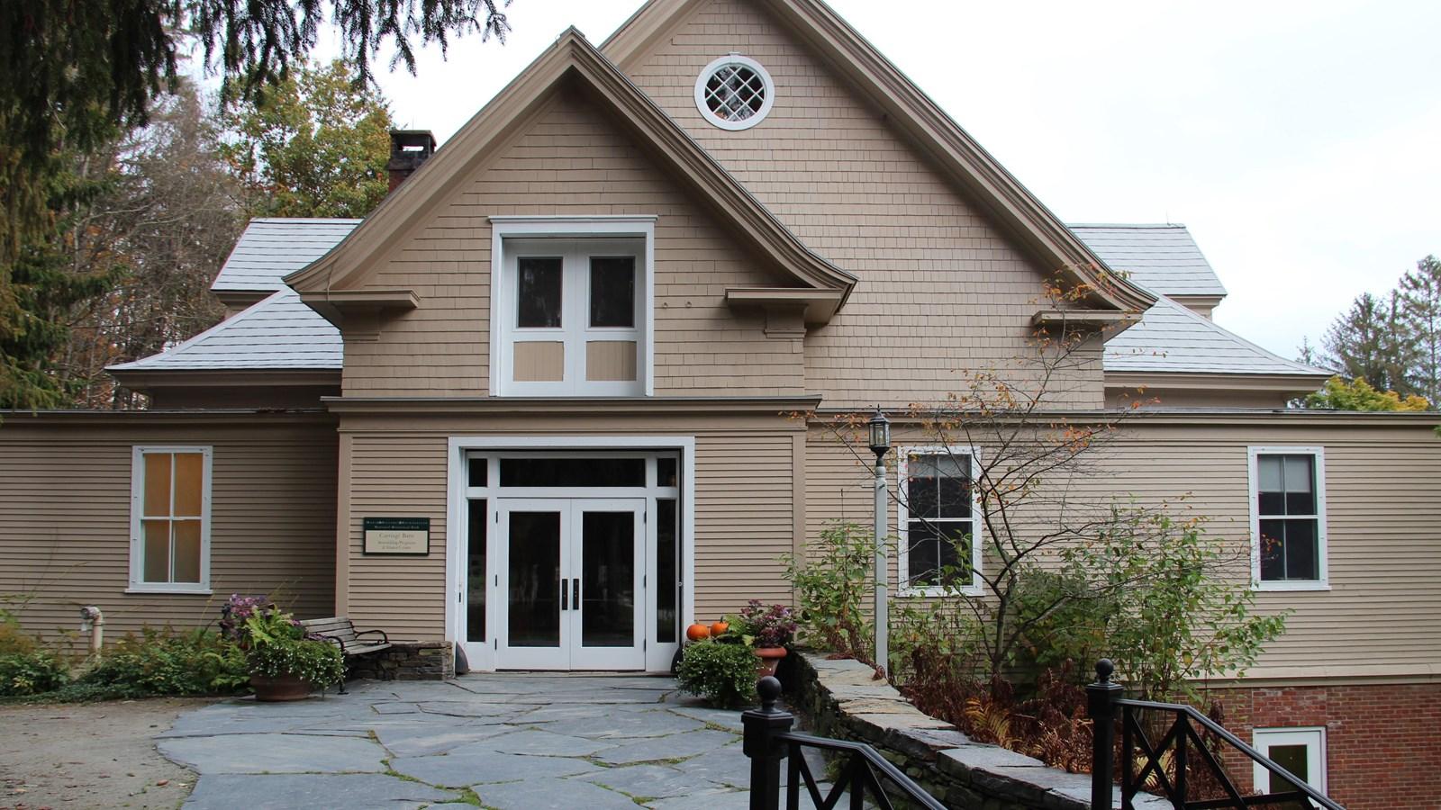 Large beige building with white trim and a stone path on an overcast day.
