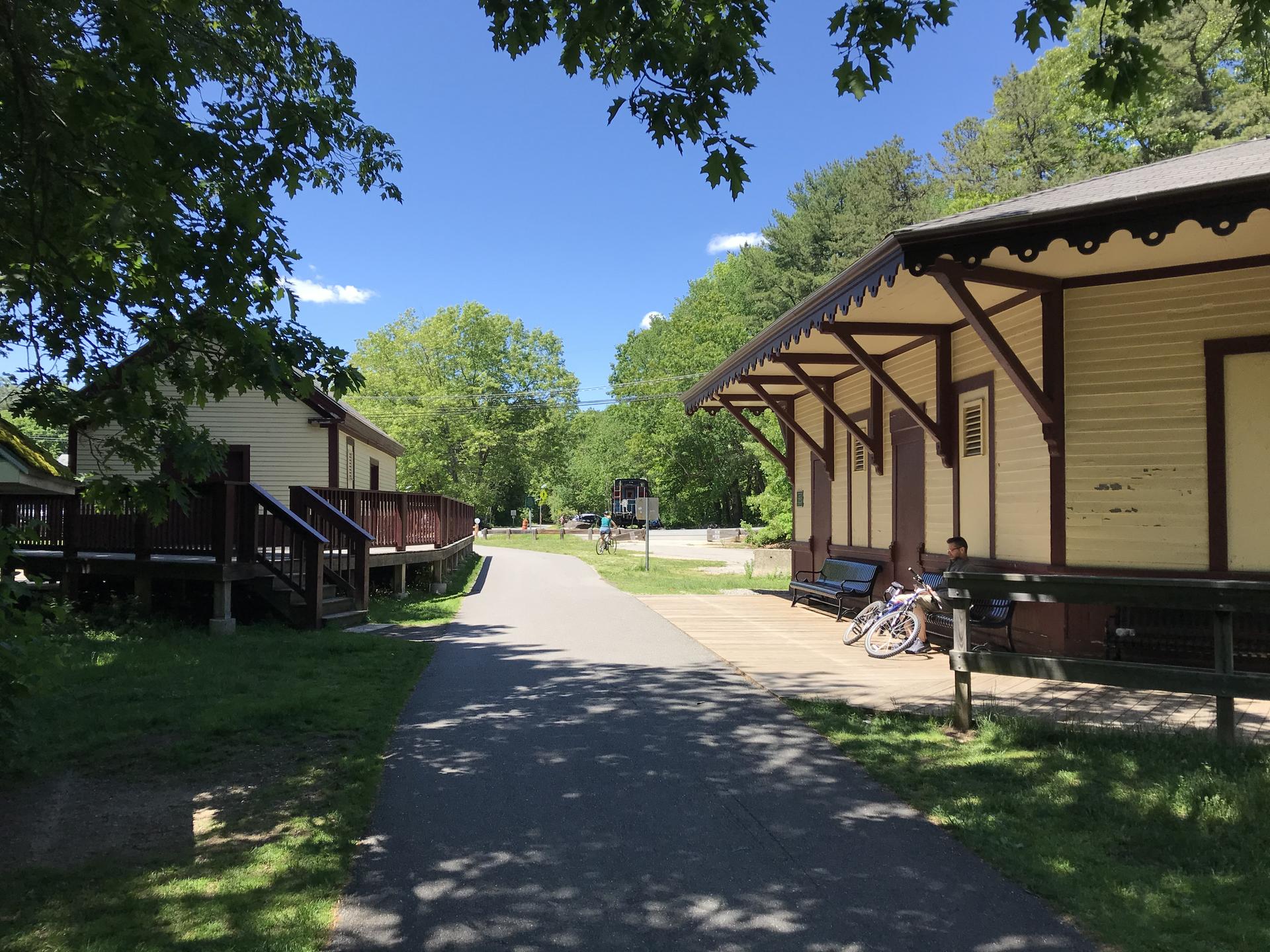 Sunny day with two historic buildings beside a paved path and parked bicycle.